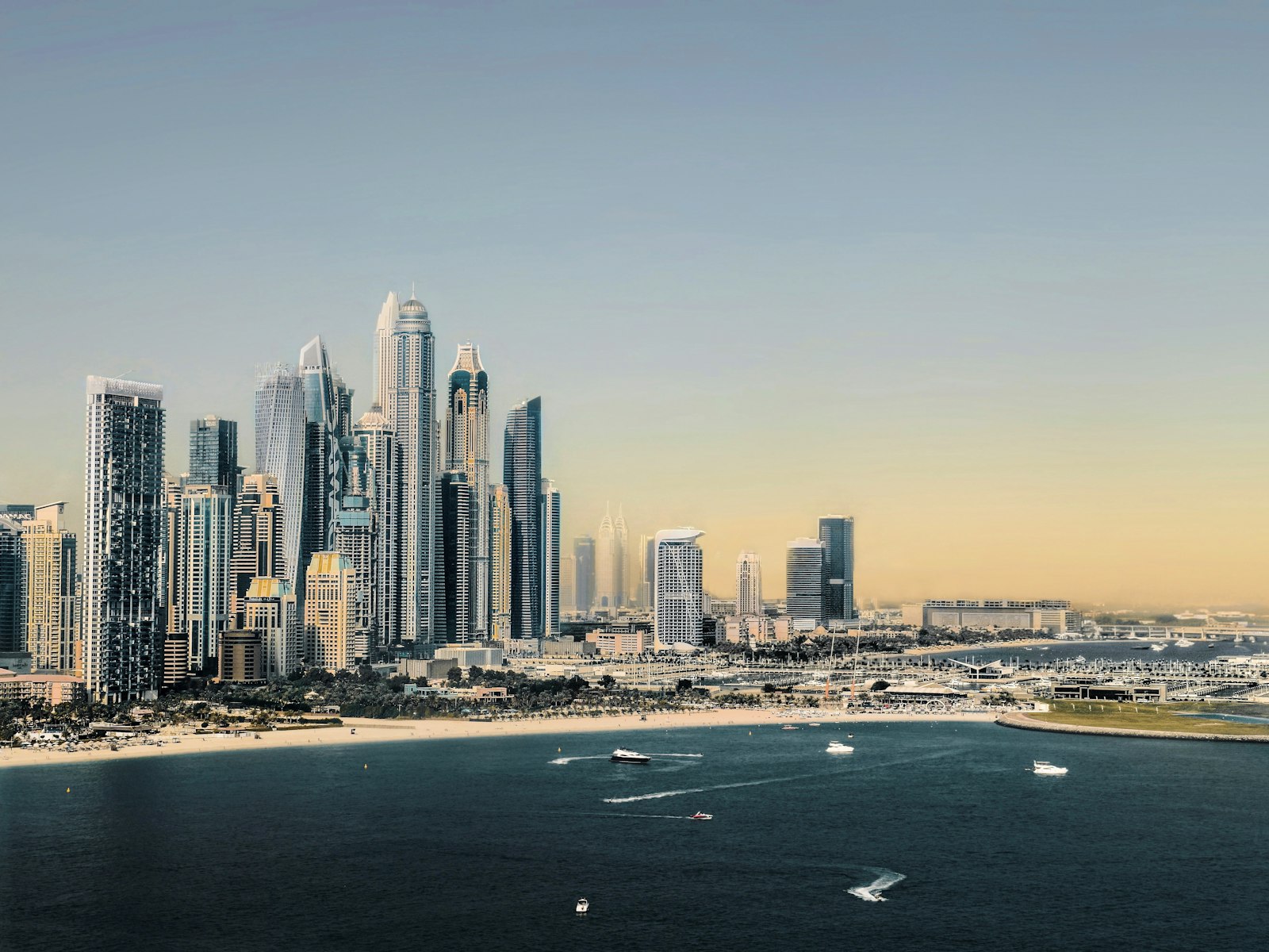 Family walking along JBR beach with Dubai Marina skyscrapers behind them