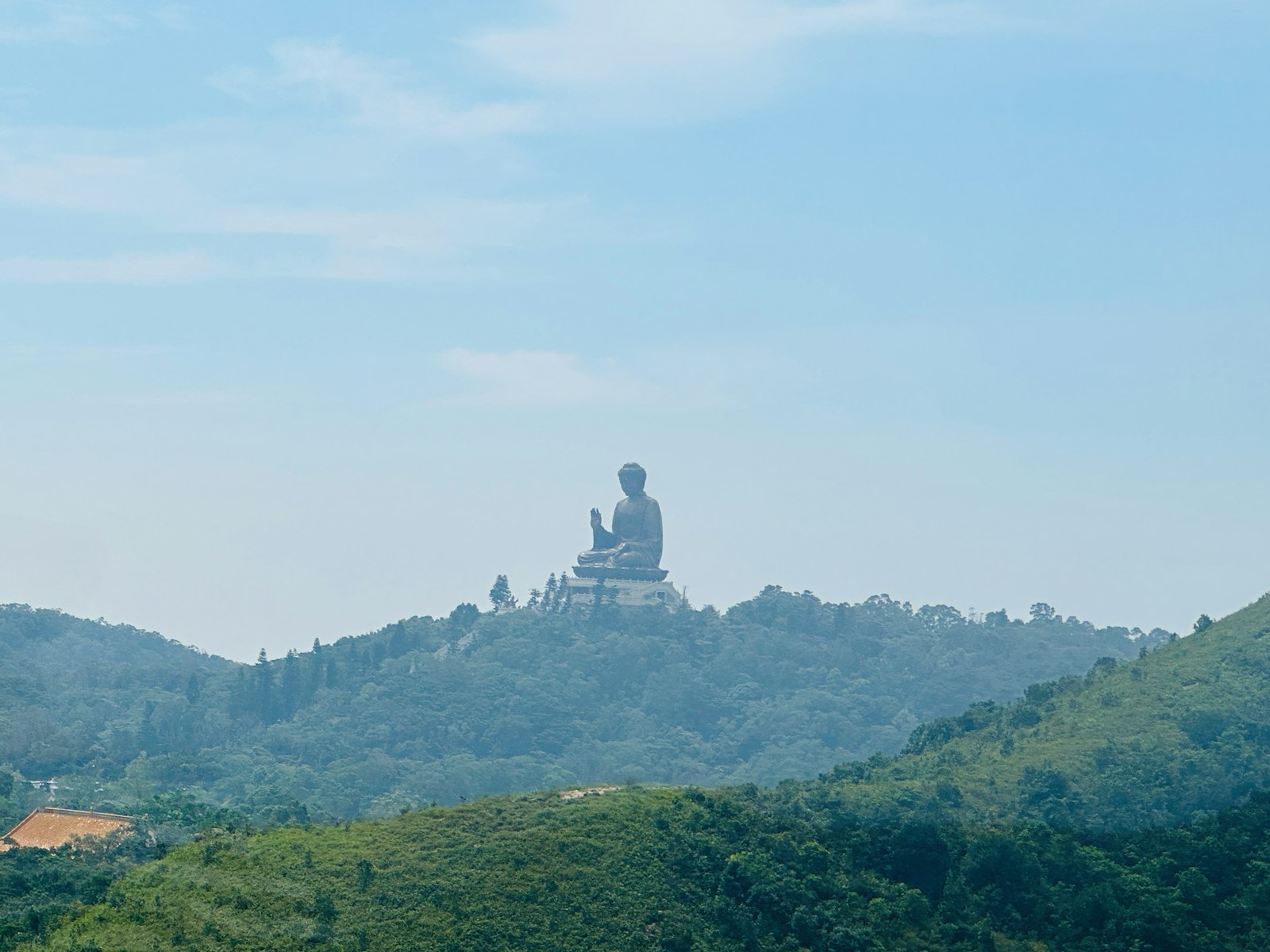 Couple standing before the Tian Tan Big Buddha statue on Lantau Island with cable car in background