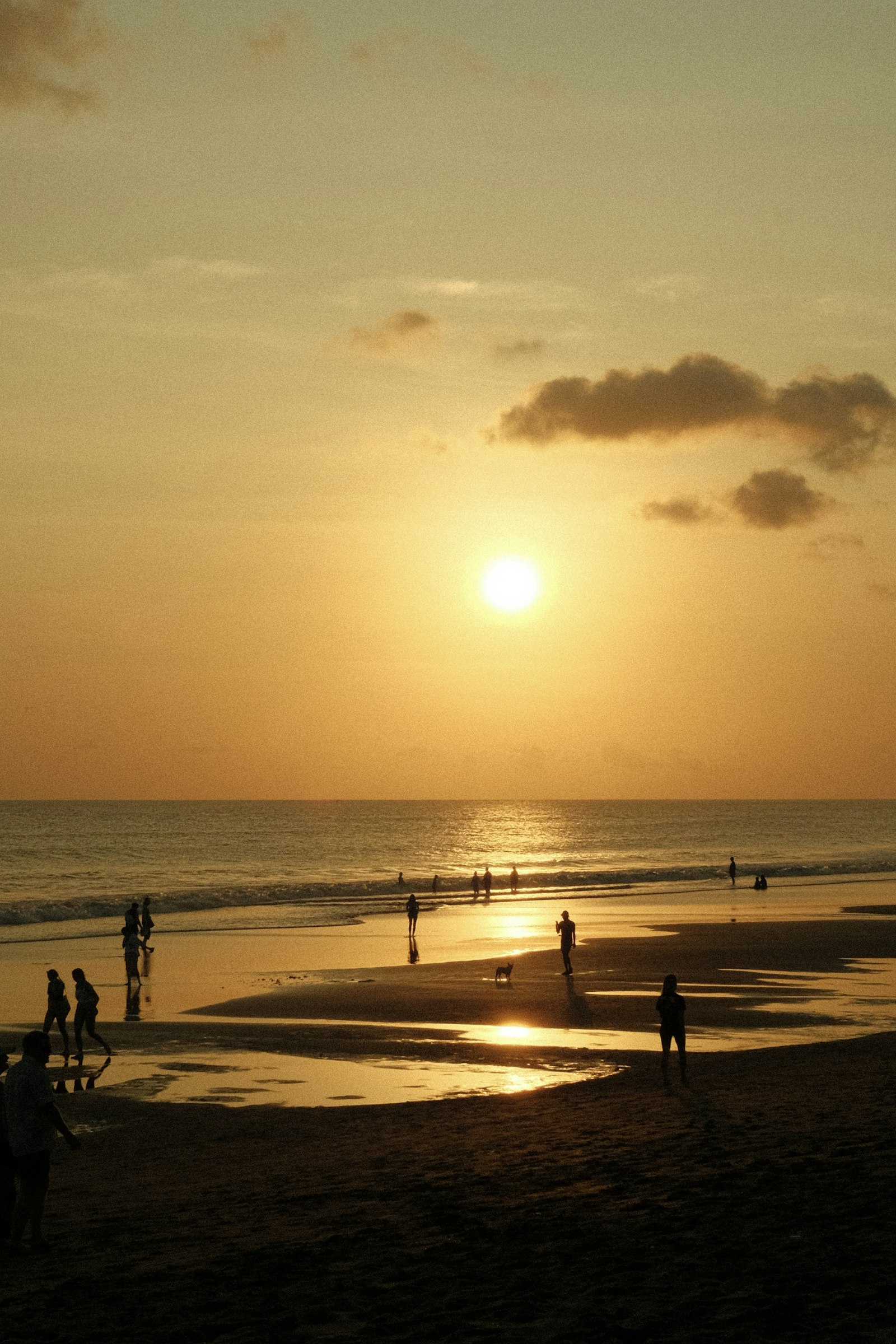 Seminyak Beach at golden hour with surfers silhouetted against the sunset