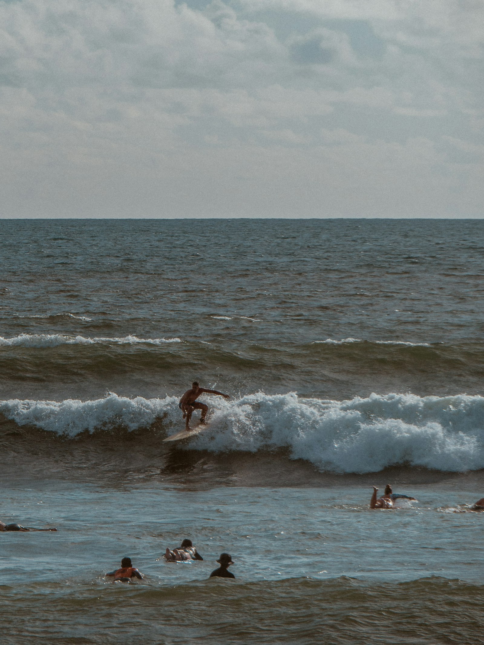 Surfer paddling out at Batu Bolong Beach in Canggu with black volcanic sand
