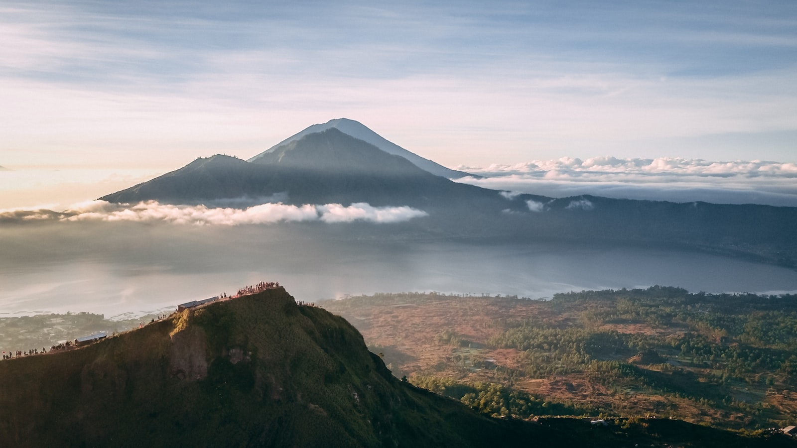 Couple watching the sunrise together from the summit of Mount Batur above the clouds