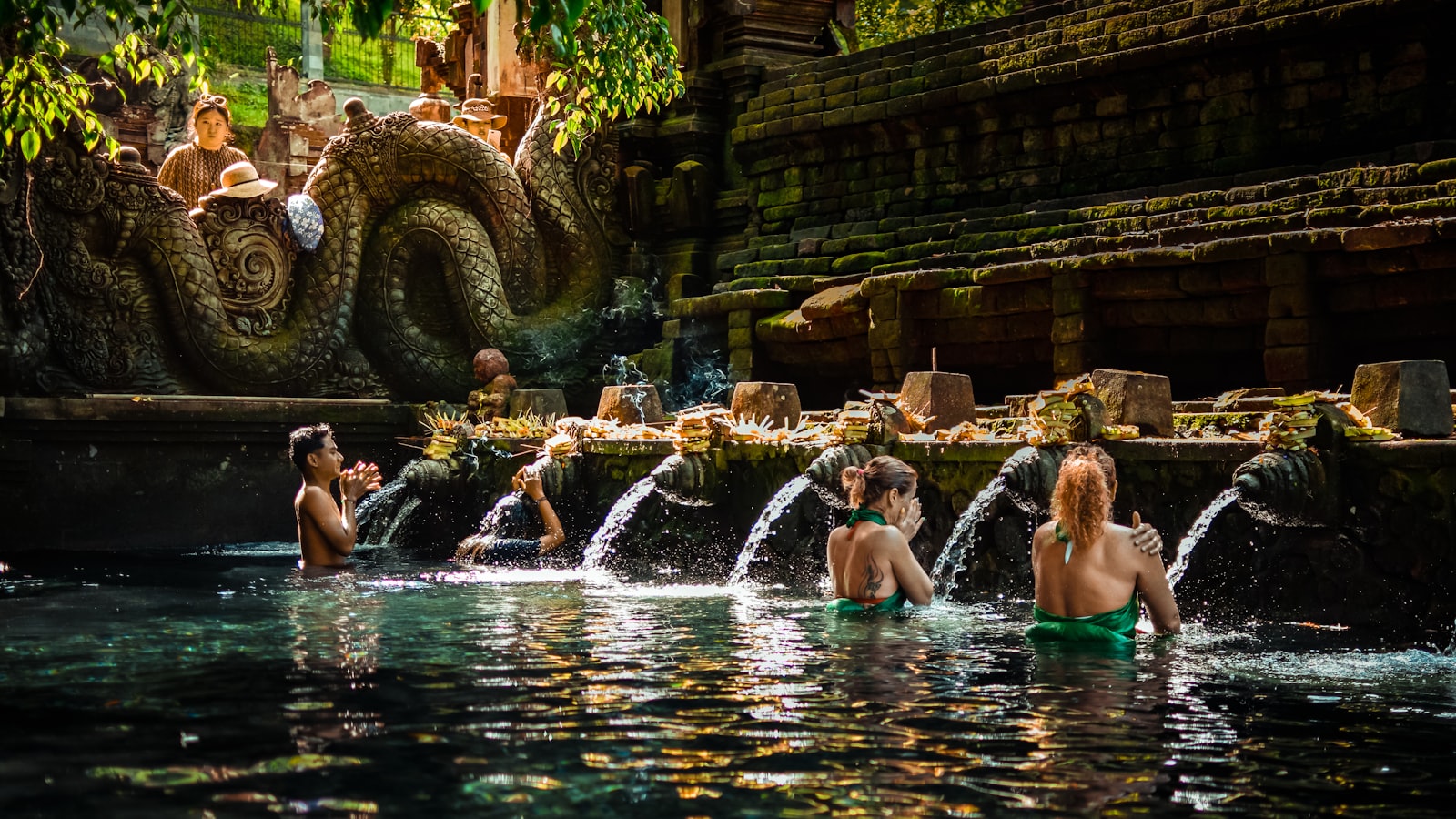 Couple in sarongs performing a purification ritual under the water spouts of Tirta Empul temple